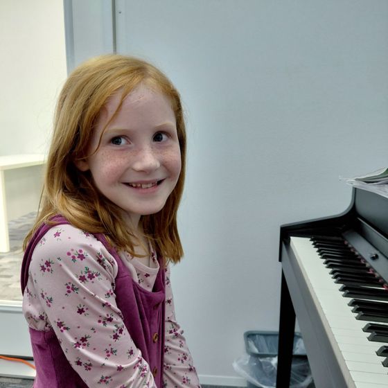 Smiling girl sitting at the piano at Grace Notes Apopka